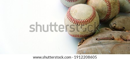 Old baseballs with glove isolated on white background beside sports game equipment.
