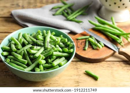 Fresh green beans in bowl on wooden table, closeup. Space for text Royalty-Free Stock Photo #1912211749