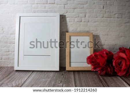 
Photo frame to fill in and bouquet of roses on white brick wall.