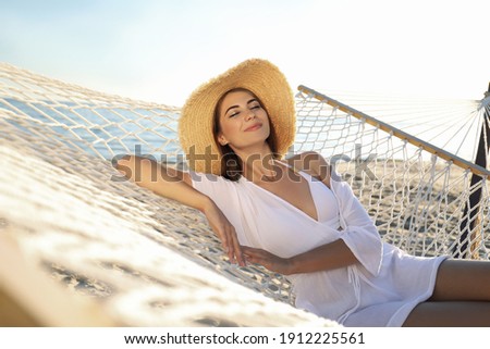 Young woman relaxing in hammock on beach