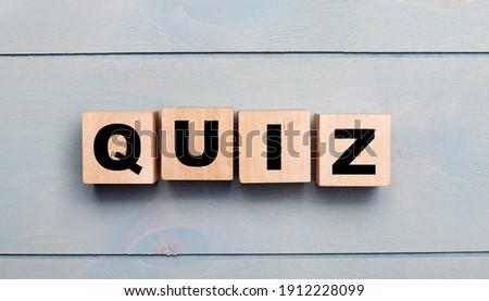 Wooden cubes with the text QUIZ on a light blue wooden background.