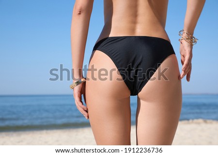 Young woman with beautiful body on beach, closeup