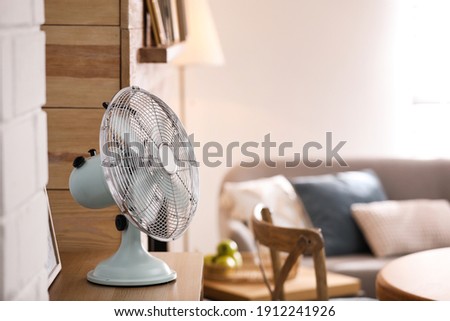 Modern electric fan on wooden table in living room. Space for text Royalty-Free Stock Photo #1912241926