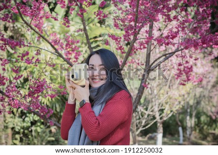 Pretty woman takes a picture of blooming cherry blossoms at garden.