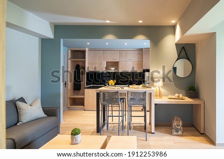 Modern grey and wooden interior of small studio apartment. Front view of hotel flat room witn kitchen, living, bedroom in single space Royalty-Free Stock Photo #1912253986