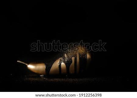 a golden pear lies on a black background