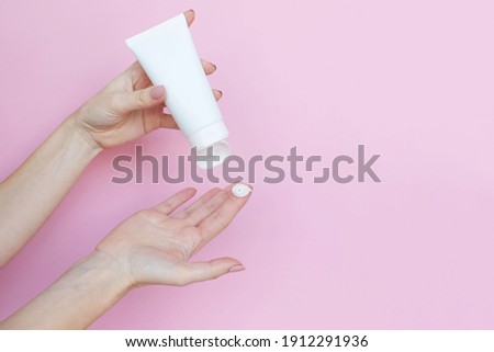 
Woman's hands with a tube and a swatch of cream on a pink background. Cosmetic products concept. Copy space Royalty-Free Stock Photo #1912291936
