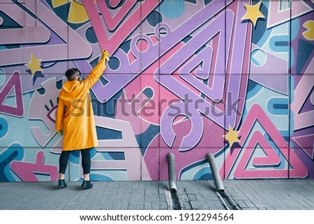 Street artist painting colorful graffiti on wall. Modern urban art concept Royalty-Free Stock Photo #1912294564