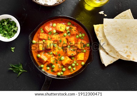 Paneer butter masala. Indian style cottage cheese curry in frying pan on black stone background. Top view, flat lay Royalty-Free Stock Photo #1912300471