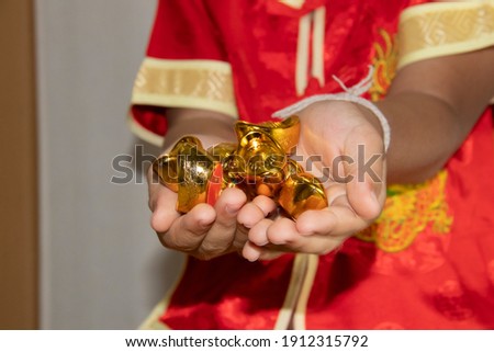 Happy little asian man in traditional chinese dress smiles and receives gold happy chinese new year concept
