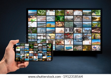 man holding mobile phone with many icons of video service on demand on background Oline TV VOD provider. Interface of video distribution service. Subscription Streaming video. Media TV on demand Royalty-Free Stock Photo #1912318564