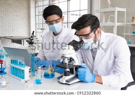 Health care researchers working in life science laboratory. Male research scientist and supervisor preparing and analyzing microscope slides in research lab. The invention of the coronavirus vaccine. Royalty-Free Stock Photo #1912322860