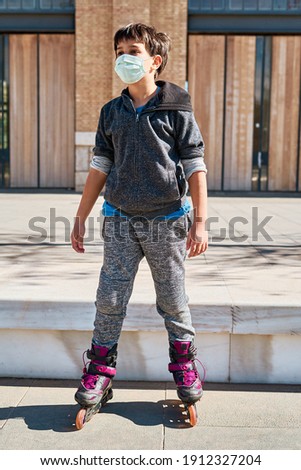 A Vertical photo of a Caucasian boy with a mask, with skates in the park. New normal pandemic Covid 19