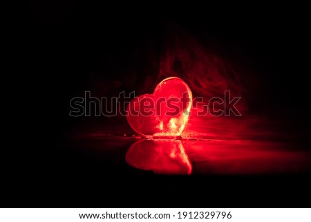 Valentines background. Valentine's Day heart on a dark wooden table. Burning ice hearts. Heart in fire. Dark toned foggy background. Selective focus