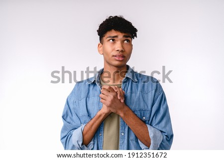 Begging young mixed-race man in casual outfit isolated over white background