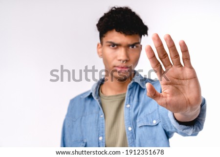 Handsome young mixed-race man showing stop gesture isolated over white background