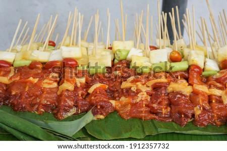 Bulk raw barbecues are stacked on banana leaves.