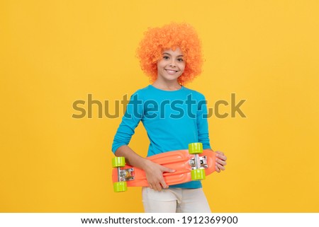 april fools day. happy childhood activity. girls birthday party. happy funny kid in wig. cheerful child holding penny board. teen girl with fancy hairstyle. being a clown.