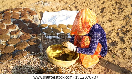 Traditional Indian woman with covering face and making handcraft Cow dung cakes for Holi festival. Religious cow dung cakes for Holi festival in India. Royalty-Free Stock Photo #1912370737