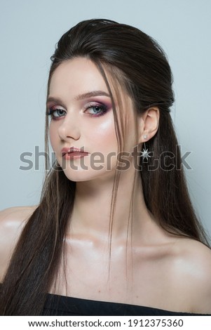 close-up portrait of a young beautiful girl on a gray background. close-up portrait of a beautiful young brunette girl with long hair and evening makeup