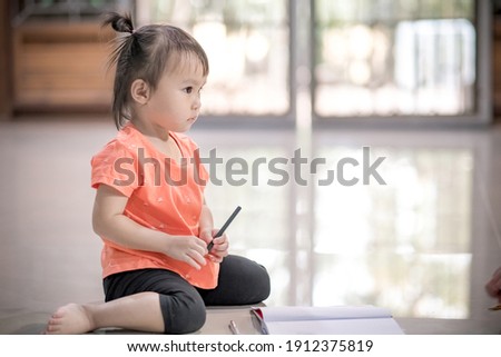 Little asian girl having fun on floor, girl  holding pencil. Soft focus. Copy space.