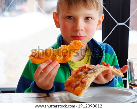 portrait of a boy greedily eating pizza 2021