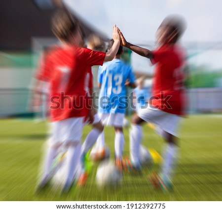 Young Boys in a Team Doing High Five on Training Unit. Happy Multiracial Group of Kids Football Players. Children Making High Five as  a Symbol of Fairplay Royalty-Free Stock Photo #1912392775
