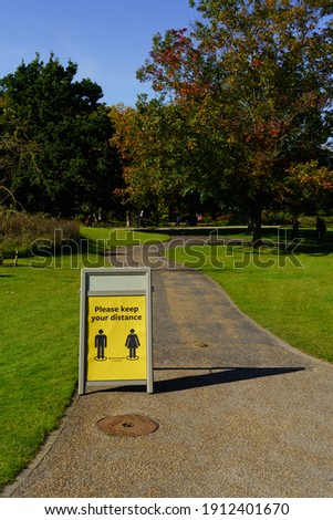 A-Stand displaying a yellow Covid-19 message on a public garden trail. 