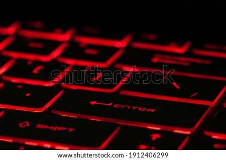 Enter key. Red backlight, backlit on gaming laptops computer in the dark. Close up
