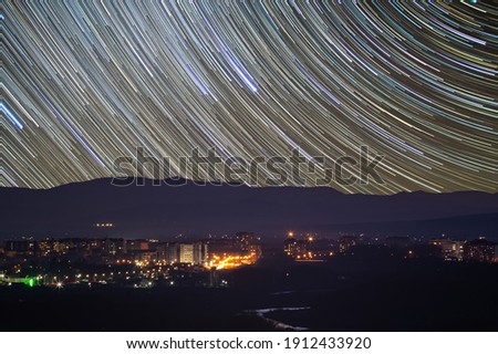 Traces of stars in the sky against the background of mountains and the city