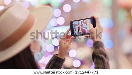 Woman use of mobile phone to take photo with christmas decoration at night