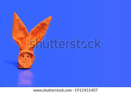orange origami bunny on a blue background. Blank for text greeting card on the theme of Easter.
