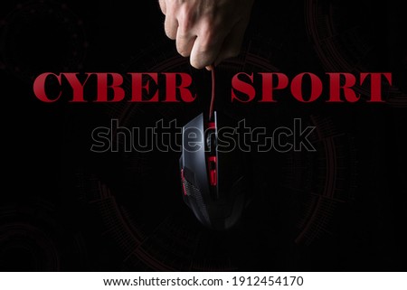 Cybersport. The concept of computer games. A male hand holds a computer mouse on a black background. Modern games