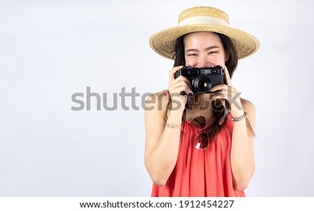 Portrait of asian beautiful woman wearing hat and holding camera while standing on white background. Summer and travel Concept.