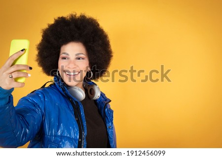 woman talking with smartphone, happy smiling, makes selfie, urban clothes and headphones, copy space