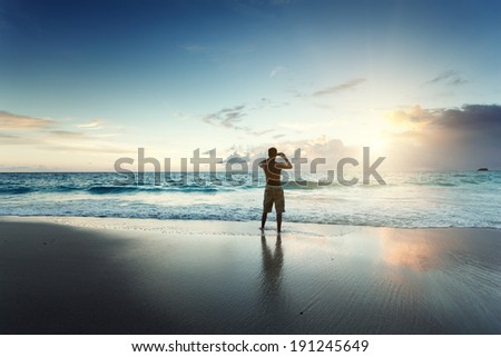 young man on the beach take photo on mobile phone