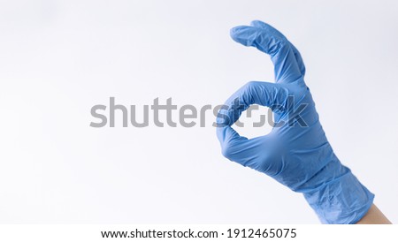 A hand in a medical glove shows the ok symbol on a white background. Baner with medical theme.