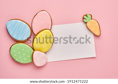 Easter greeting card with colorful rabbits, eggs, chickens and carrots gingerbread cookies on pink background with copy space. Mock up. Banner. Top view.