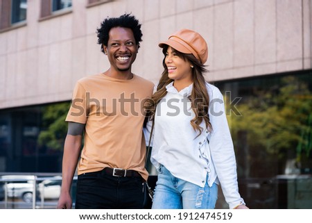 Tourist couple carrying suitcase while walking outdoors.