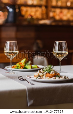 Stuffed mushrooms filled with cheese, mushroom stem and microgreen on the white plate with a glass of wine in the restaurant Royalty-Free Stock Photo #1912477393
