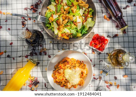 A summer picnic atmosphere, tablecloth on the lawn with plates of healthy food and fruit drinks. Flat lay food. Olive oil, salads, sandwich, quinoa salad, vegan burger
