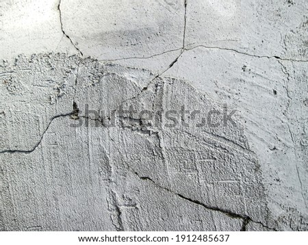 Smeared concrete background with a crack. Damage on a light rough surface.