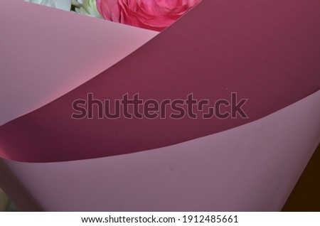 Female hands unfold craft paper next to a bouquet of lavender flowers and wild onions on a bright yellow background. Top view.