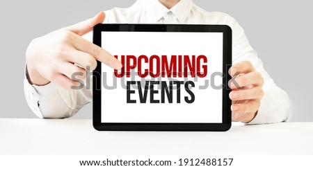Text upcoming events on tablet display in businessman hands on the white bakcground. Business concept
