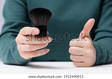 Woman is holding a new makeup brush and is showing a thumbs up gesture. Choosing of make up brush.