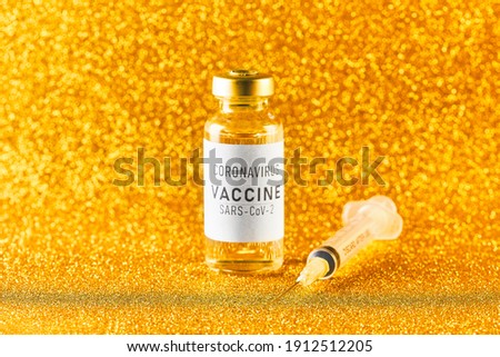 Coronavirus vaccine. Vaccine values during the acute period of the covid-19 pandemic concept. Vial and syringe on a golden background. Gold toning Royalty-Free Stock Photo #1912512205