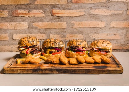 A set of four delicious hamburgers of different sizes, filled with nuggets all around