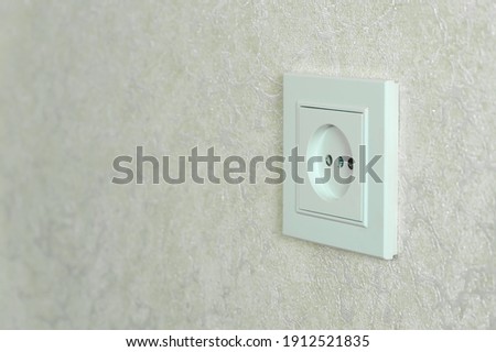 White electrical outlet on a white wall close-up with copy space, photo at an angle Royalty-Free Stock Photo #1912521835