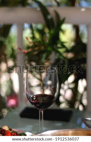Glass of red wine, served in a garden. Selective focus.
