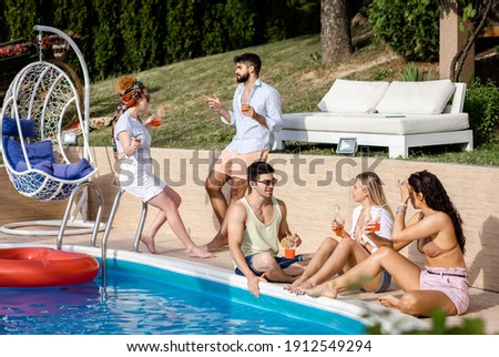 Group of friends having fun at summer vacation and enjoying a poolside party.
